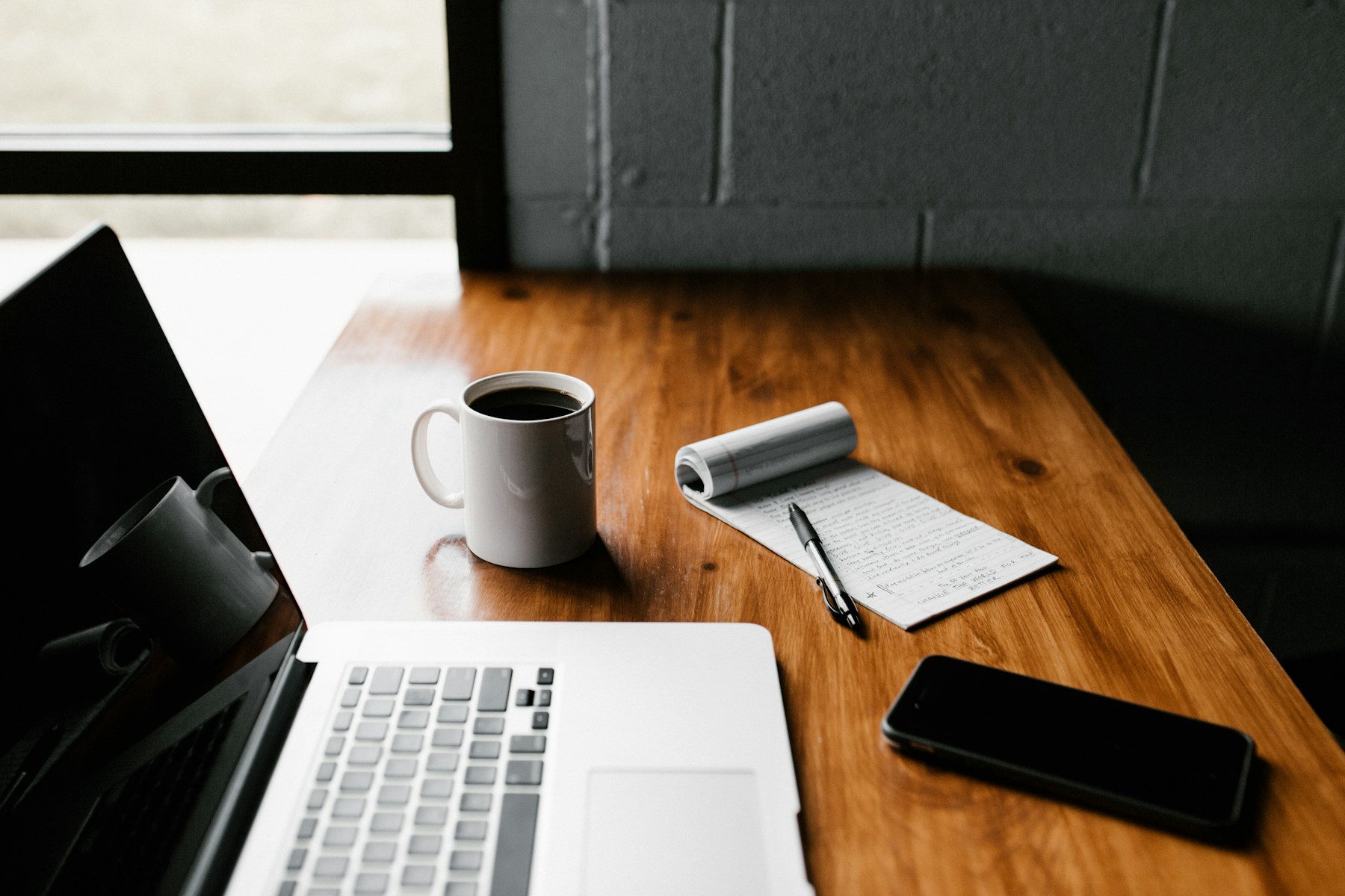 Sales planning workspace with a laptop, notebook, and coffee